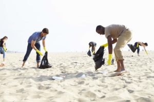 people picking up trash on a beach