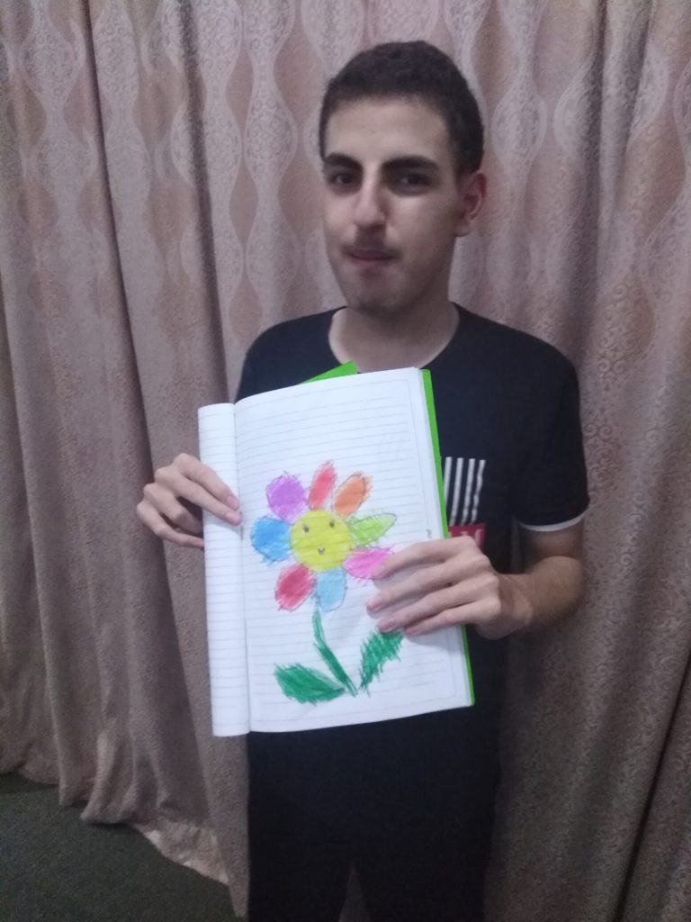 student holding a drawing of a colorful flower