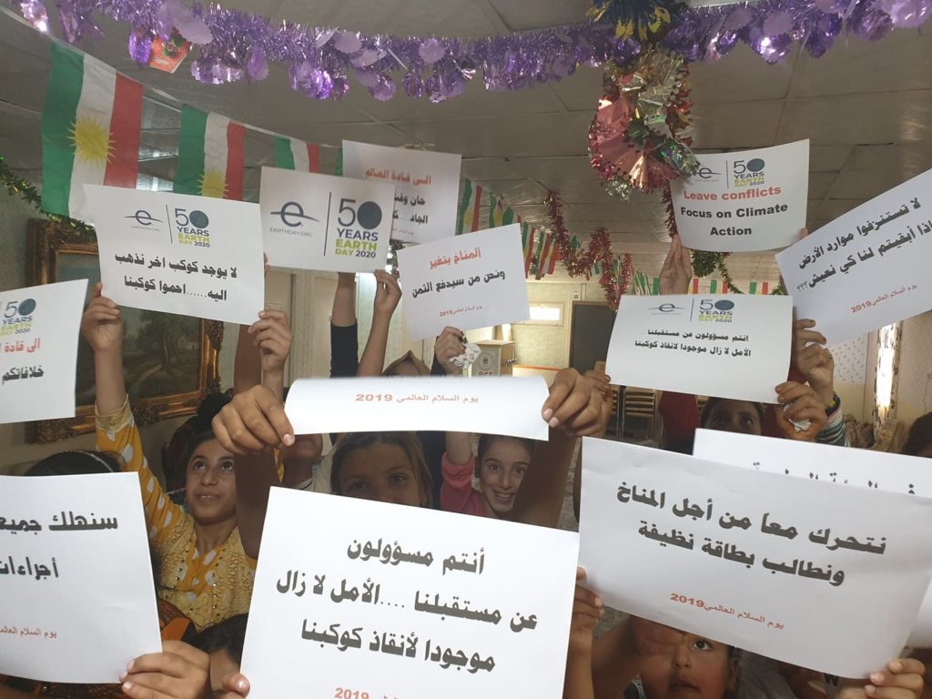 children in Iraq holding up climate flyers