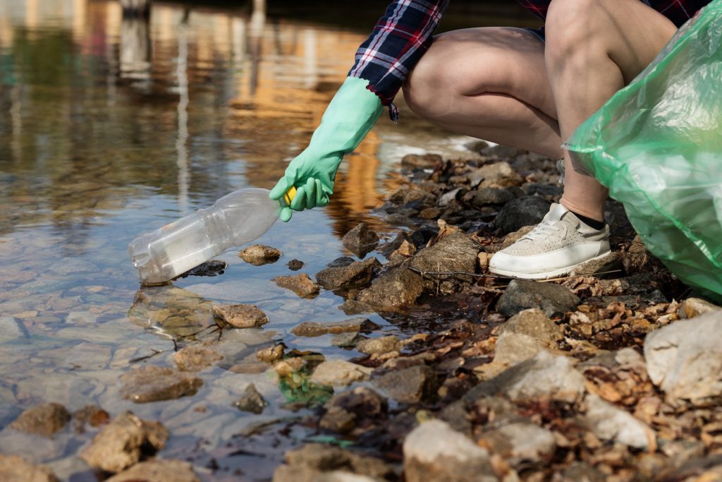 Person picking up litter out of a stream