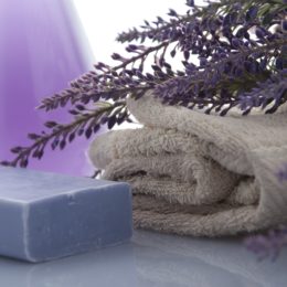 Bar of purple soap, cream colored towel and lavender flowers