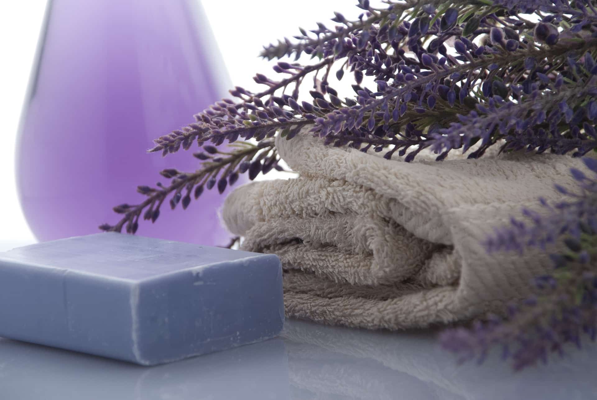 Bar of purple soap, cream colored towel and lavender flowers