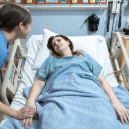 Woman in blue shirt lying on hospital bed