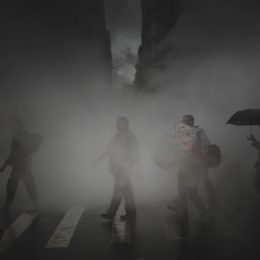pedestrians walk on a crosswalk and through steam