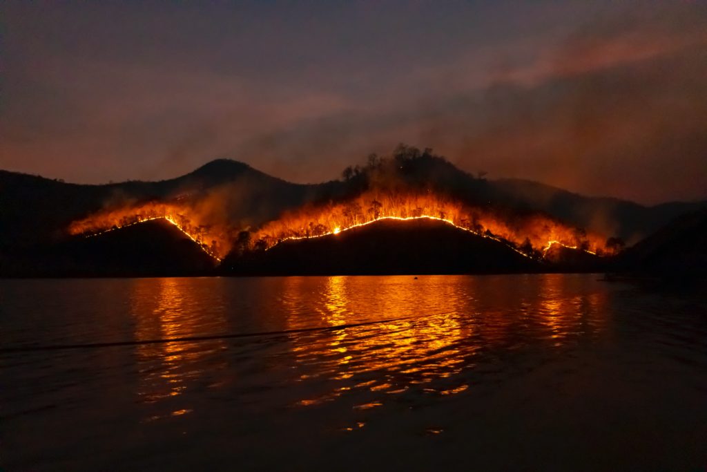 Wildfire engulfing a mountain along water