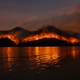Wildfire engulfing a mountain along water