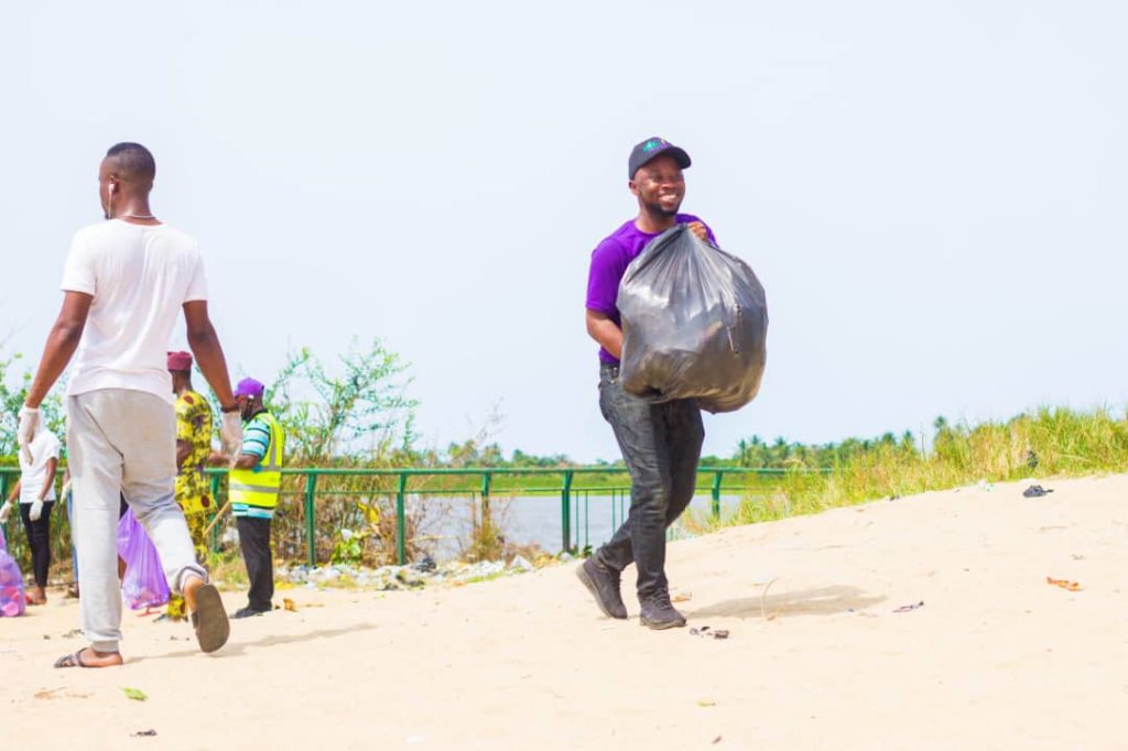 Man smiling and holding a garbage bag on a beach