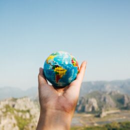 Person holding globe in front of mountains.