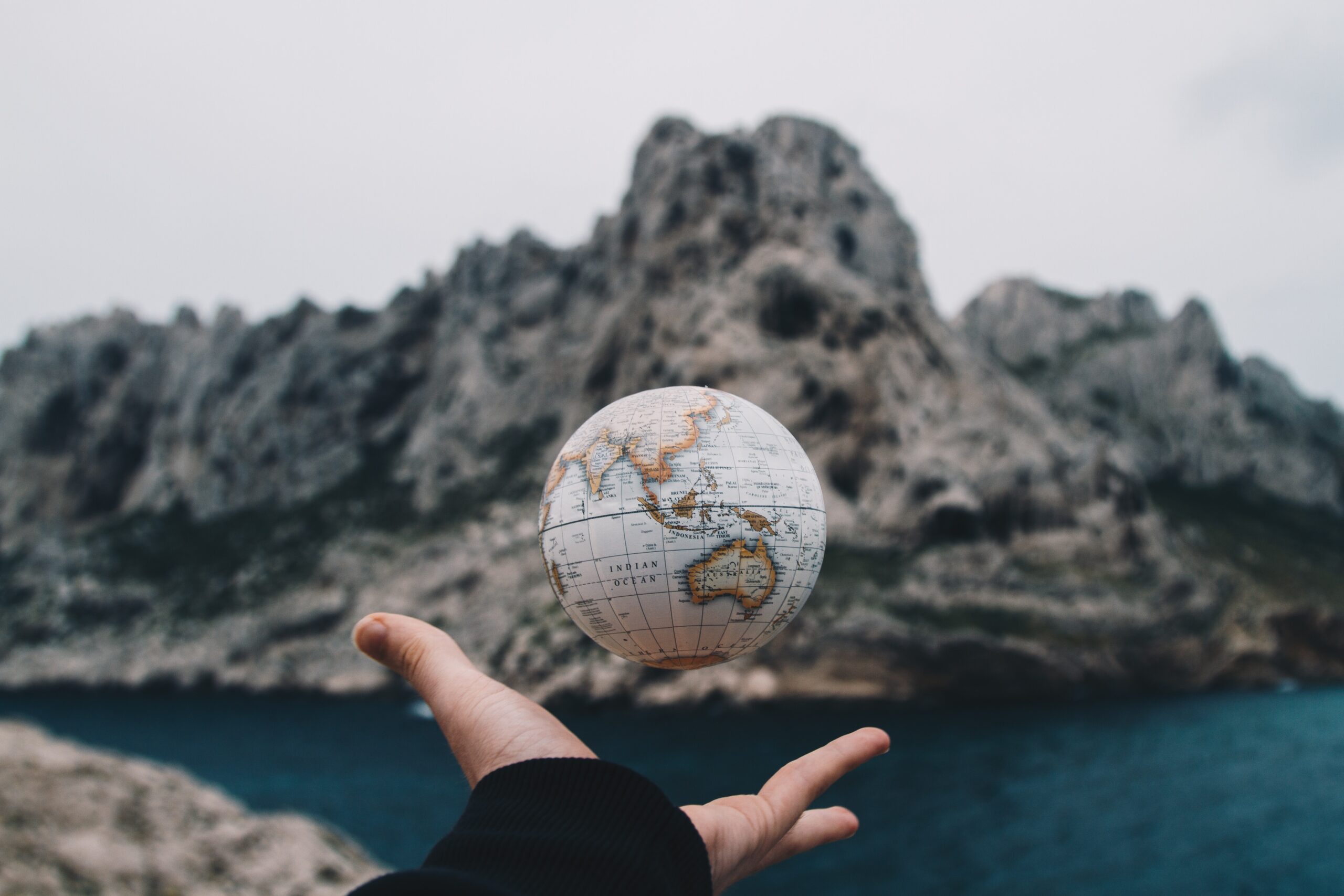 hand and globe in front of mountain