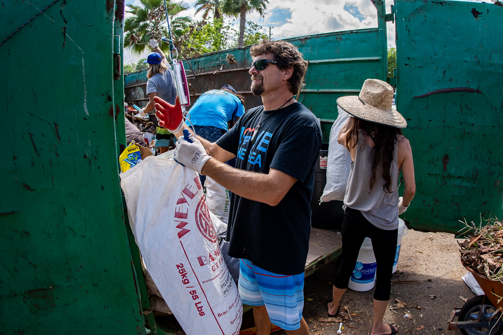 Volunteer dumping trash off into the dumpster