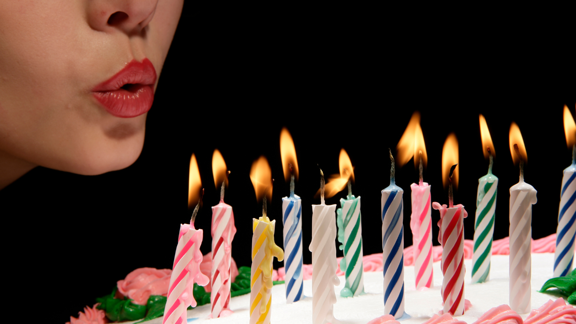 Woman blowing out birthday candles on a cake.