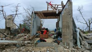 Person in a chair in a destroyed home.