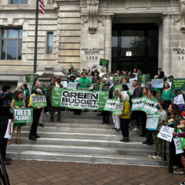 People stand on steps of DC City Hall holding banner of Green Budget Day of Action. Councilmember Charles Allen [center], joined by local and national environmental leaders, addresses the media during the DC Green Budget Day of Action.