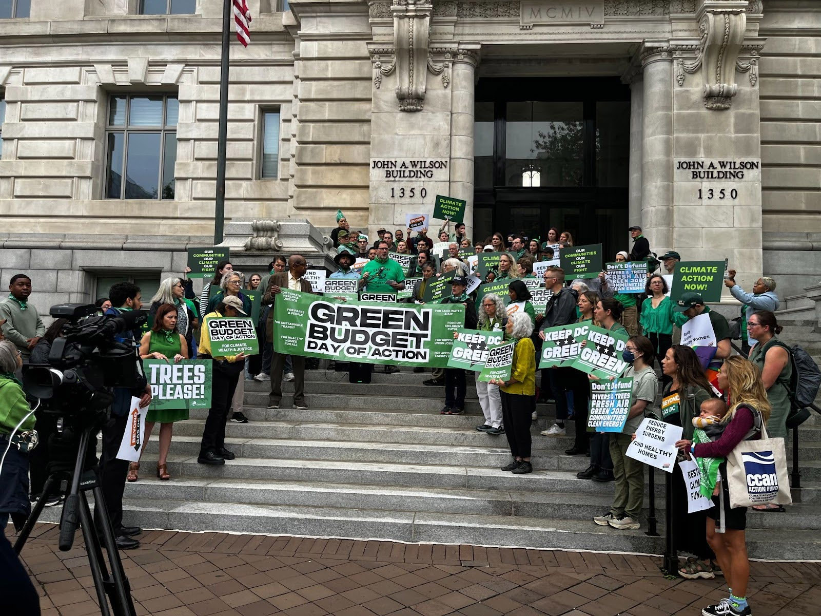 People stand on steps of DC City Hall holding banner of Green Budget Day of Action. Councilmember Charles Allen [center], joined by local and national environmental leaders, addresses the media during the DC Green Budget Day of Action.