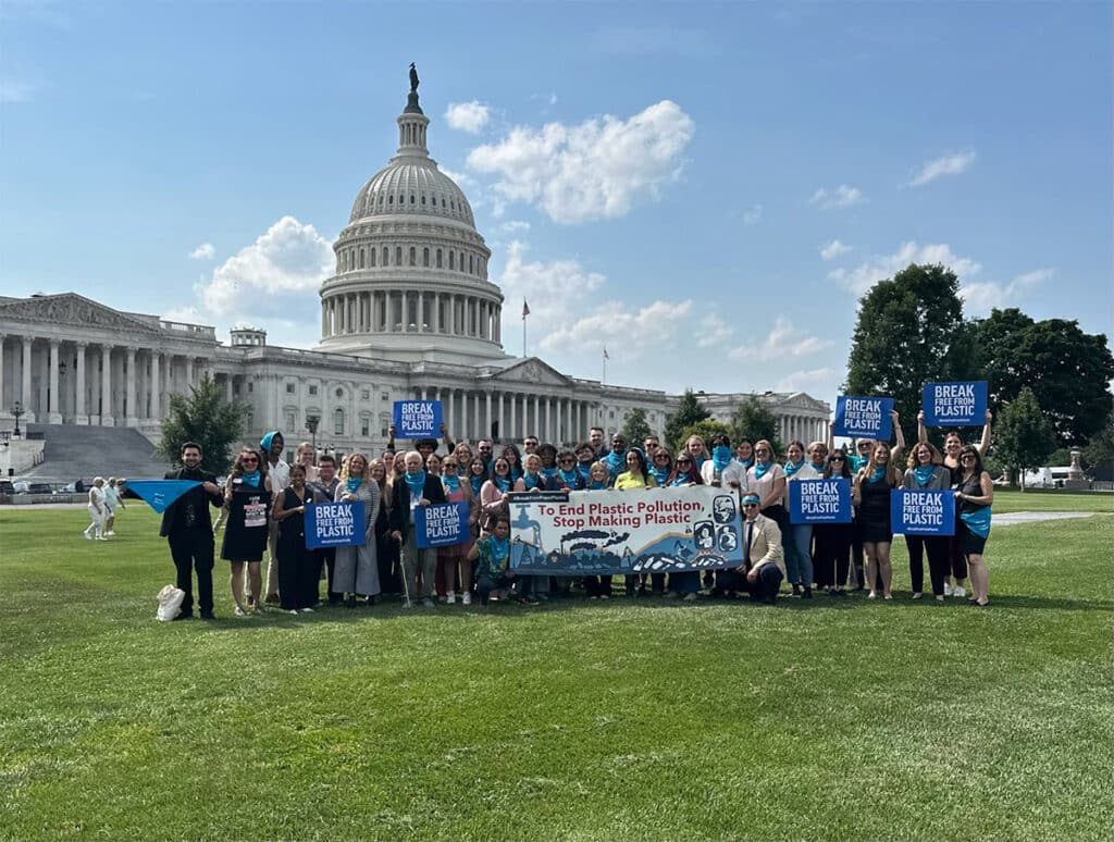 Coalition of many members standing outside the Capital, with signs and a banner