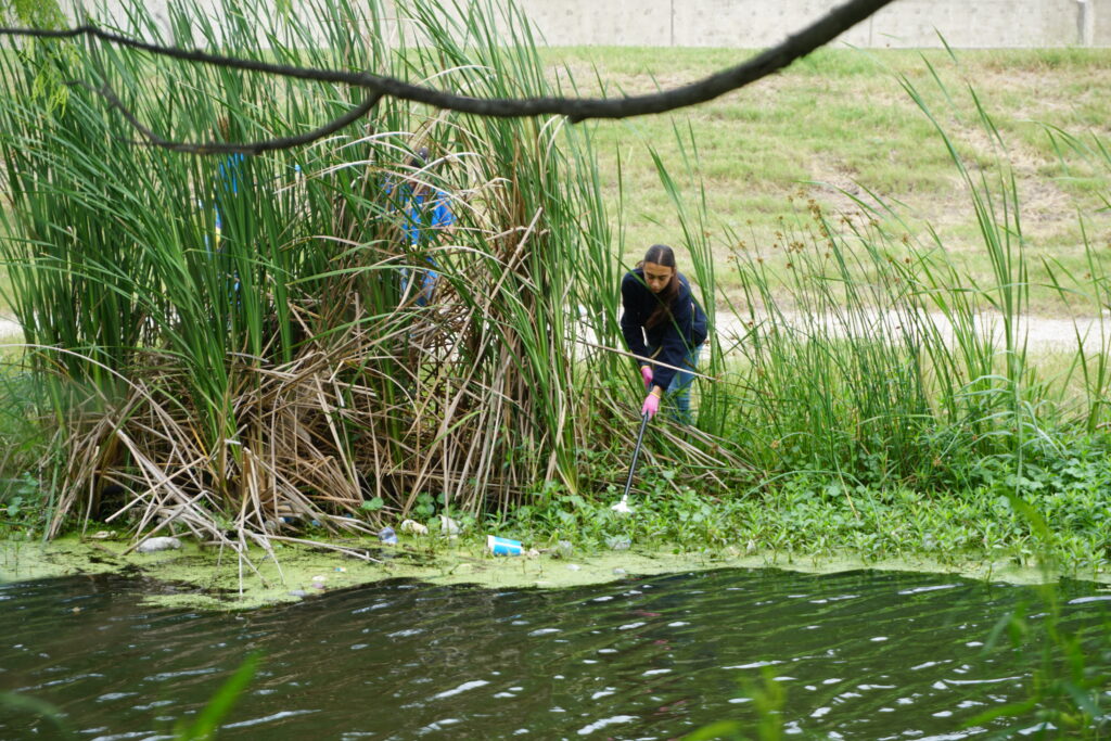 Volunteer cleaning up trash out of a river.