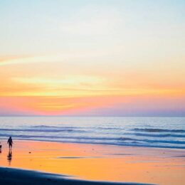 Two persons standing at beach side during low tide and golden hour