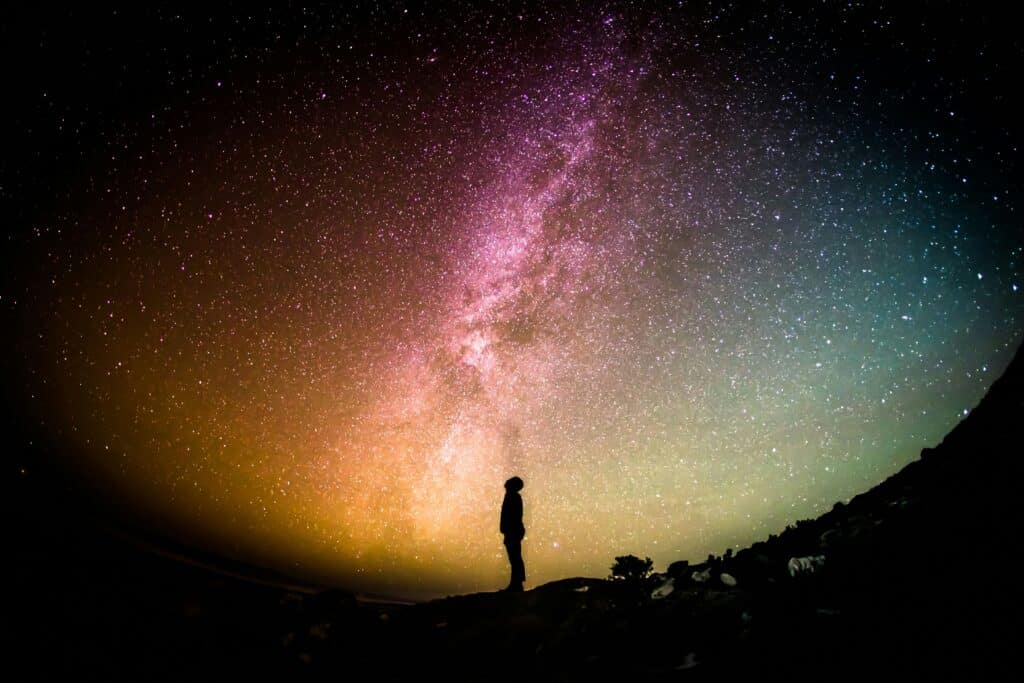 Person looking up at a colorful night sky