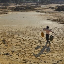 Man carrying water on cracked earth