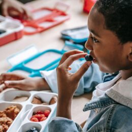 Blakc child eating food off a tray