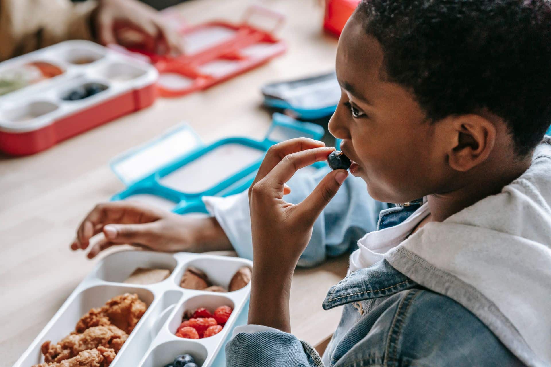 Blakc child eating food off a tray