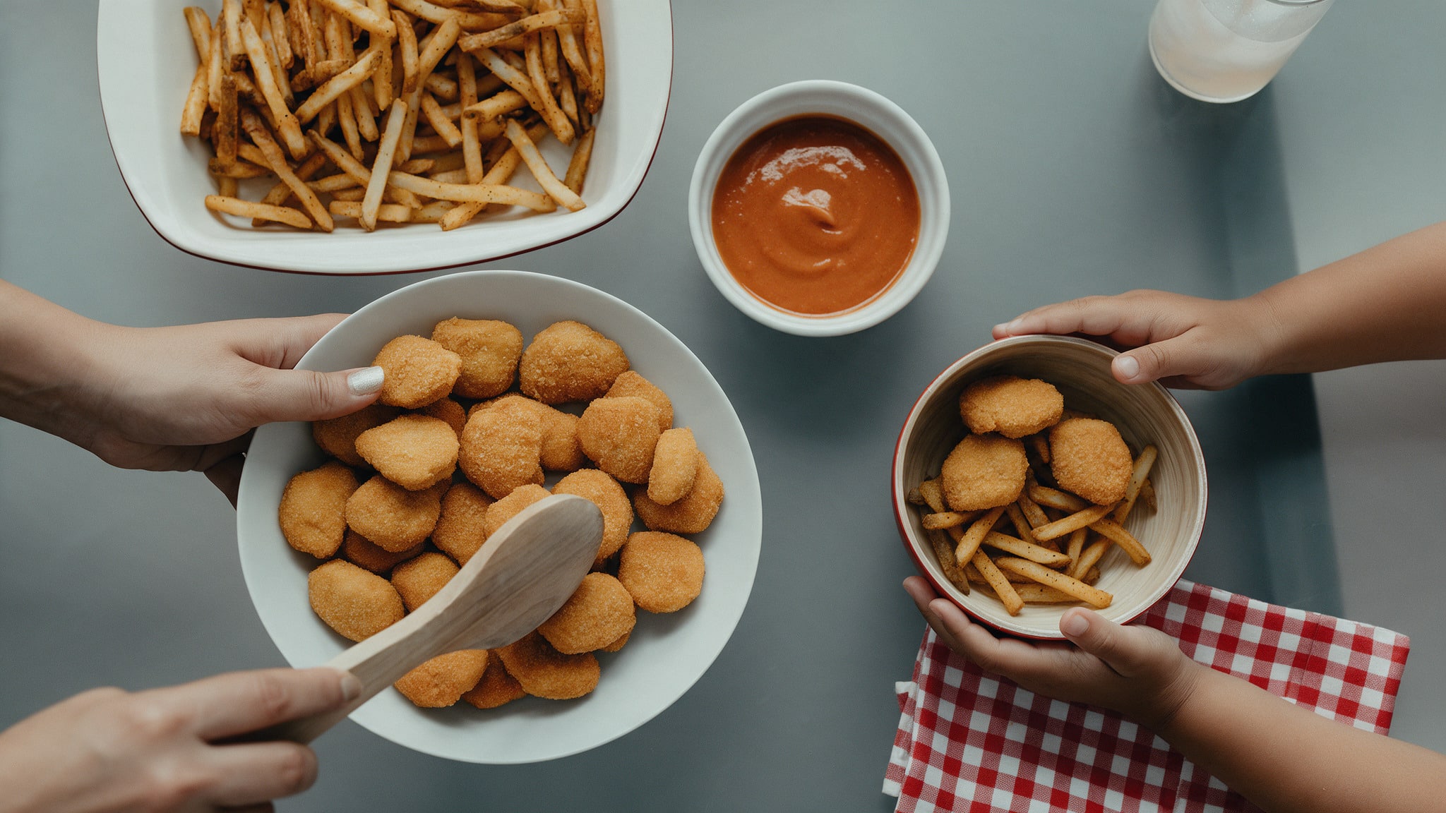 Hands reaching for chicken nuggets and fries